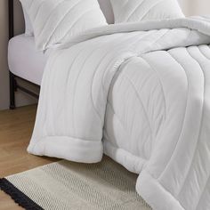 a bed with white comforter and pillows on it