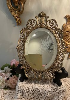 there is a mirror on the table with flowers in front of it and two mirrors behind it