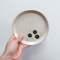 a hand holding a white bowl with black sprinkles on it