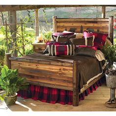 the bed is made with wood and has red plaid bedspread, pillows, and throw pillows