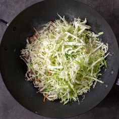 shredded cabbage being cooked in a wok