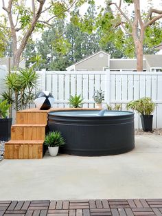 an outdoor hot tub surrounded by potted plants