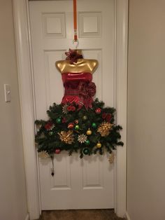 a door decorated for christmas with a dress and wreath on the front entrance to a house