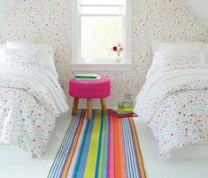 two beds in a small room with polka dots on the walls and colorful rugs