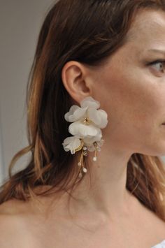 a woman wearing large white flowers on her ear