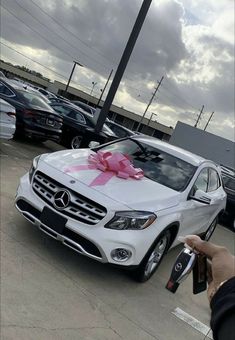 a white car with a pink bow on it's hood is parked in a parking lot