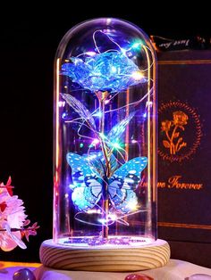 a glass jar with some lights in it on top of a table next to flowers