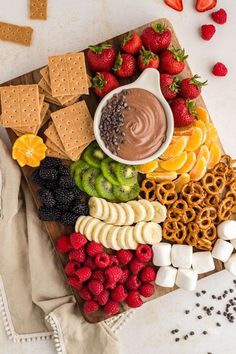 a platter filled with fruit, crackers, pretzels and other snacks