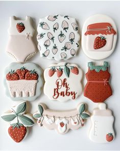 decorated cookies are arranged in the shape of baby's clothes and strawberrys on them