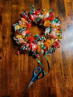 a pair of scissors sitting on top of a wooden floor next to a christmas wreath