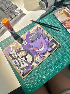 a table topped with lots of crafting supplies on top of a white desk next to a keyboard