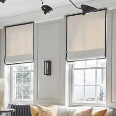 a living room filled with furniture and two windows covered in blind shades on the walls