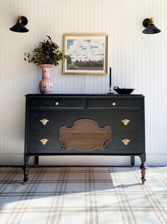 a black dresser with an ornate design on the front and side, against a white wall