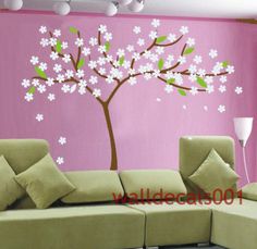 a living room decorated in pink and green with white flowers on the tree wall decal