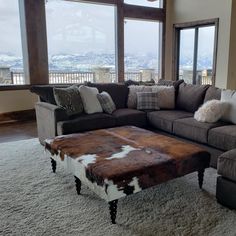 a living room filled with furniture and a large window covered in snow capped mountains behind it