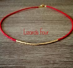 a red string bracelet with gold beads on it and the words lizards four written in english