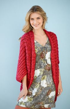 a woman wearing a red cardigan standing in front of a blue background