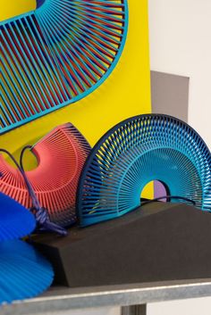 colorful plates and vases sitting on top of a metal table in front of a yellow wall