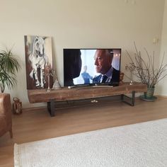 a flat screen tv sitting on top of a wooden shelf in a living room next to a couch