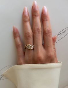 a woman's hand with a gold ring on top of her left hand, resting against a white surface