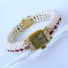 Beautiful One of A Kind stunning vintage working Winding Dial Watch is reworked into a timeless and elegant Pearl, Ruby and 14k Yellow Gold piece. Stamped and made in all solid 14k Yellow Gold, this timeless watch is revived by Tapered Baguette Rubies set on each side which perfectly contrasts the 14k Yellow Gold. A stunning band of round white Seed Pearls, Faceted Rubies and solid 14k Yellow Gold findings are all intricately woven together to frame this vintage piece. This top of the band is wo Classic Yellow Gold Diamond Watch With Jubilee Bracelet, Timeless Yellow Gold Diamond Watch For Wedding, Classic Yellow Gold Jewelry And Watches For Anniversary, Elegant 14k Gold Watch With Diamond Hour Markers, Elegant 14k Gold Watches For Formal Occasions, Timeless 14k Gold Watch For Anniversary, Classic Watch With Box Clasp For Anniversary, Classic Formal Jewelry And Watches With 17 Jewels, Wedding Jewelry With Diamond Hour Markers