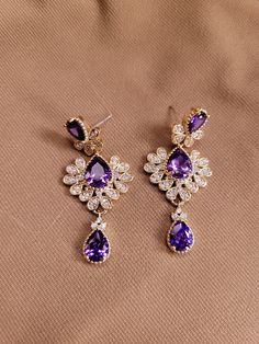 The earrings are three tiered with tear drop one and two carat amethyst stones and a zircon accented deco design.  Total 4 carats amethyst.  .88 carats zircon.  14K gold plated. Elegant Purple Jewelry For Evening, Elegant Purple Evening Jewelry, Luxury Amethyst Teardrop Earrings, Purple Crystal Drop Earrings For Evening, Purple Drop Crystal Earrings For Evening, Elegant Lavender Crystal Earrings For Party, Formal Lavender Earrings, Formal Jeweled Cubic Zirconia Earrings, Elegant Amethyst Teardrop Dangle Earrings