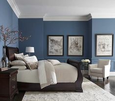 a bedroom with blue walls and white bedding in the center, two framed pictures on the wall