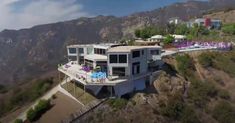 an aerial view of a house on the top of a hill with mountains in the background