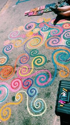 someone is drawing on the sidewalk with chalk and crayon pencils in front of them