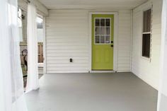 a yellow door is on the side of a white house with a green front door