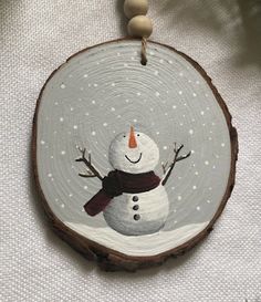 a snowman ornament hanging from a tree slice