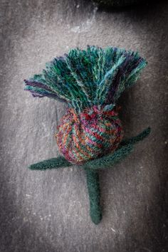 a knitted flower sitting on top of a gray surface