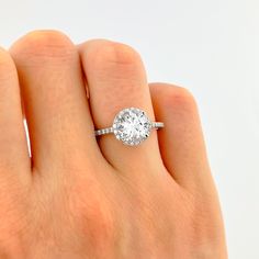 a woman's hand with a diamond ring on top of her finger and an engagement band