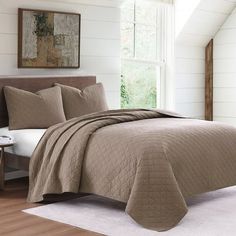 a bed in a bedroom with a brown comforter and pillows on top of it