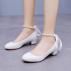 a close up of a person wearing white shoes with pearls on the ankle and heel