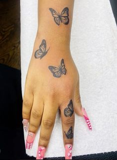 a woman's hand with butterfly tattoos on her left wrist and pink nail polish