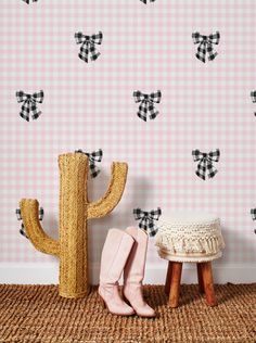 a cactus sitting on top of a wooden stool next to a wall with black and white designs