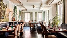 an empty restaurant with tables and chairs in front of large windows, plants on the wall