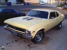 an old yellow car parked in a driveway