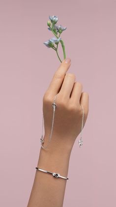 A hand holding a long silver necklace with love knots and an arm with a silver cuff with a love knot. Earrings Hoops, A Love, Long Necklace