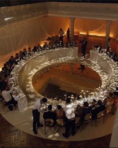 an overhead view of people sitting at tables in front of a circular table with candles on it