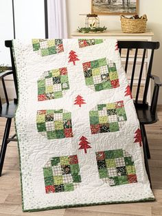 a green and white quilt on a chair in front of a table with a black chair