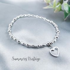 This simple and dainty sterling silver bracelet featuring a beautiful open-heart charm looks stunning worn alone or stacked alongside other bracelets for a Bohemian feel   The eclectic mix of beautiful beads are strung on high quality, strong, professional jewellers' elastic meaning there are no fiddly clasps to deal with, the bracelet can simply be rolled over the hand and onto the wrist The bracelet is elegantly presented in a beautiful jewellery pouch, complete with aftercare instructions and Dainty Adjustable Open Heart Bracelet, Dainty Open Heart Adjustable Bracelet, Elegant Sterling Silver Beaded Bracelet With Heart Charm, Sterling Silver Beaded Bracelets With Heart Beads, Sterling Silver Heart Beaded Bracelets, Minimalist Sterling Silver Heart Bracelet For Mother's Day, Elegant Sterling Silver Heart Bracelet With Round Beads, Minimalist Adjustable Beaded Bracelets With Heart Charm, Silver Bracelets With Heart Beads