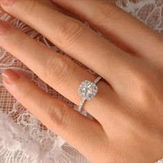 a woman's hand with a diamond ring on top of her finger and lace