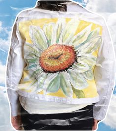 a woman wearing a white jacket with a painted flower on it's front and back