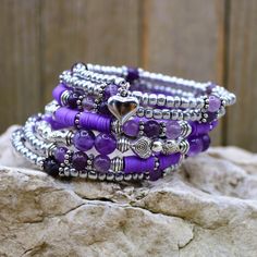 "This beautiful February Birthstone seven layer healing stone bracelet is a truly unique statement piece. The Amethyst and silver beads give that sweet and soft romantic vibe which wears well for many occasions from weekend wear to dressy wedding. The perfect gift as the one-size-fits-all feature makesgifting easy! . Made with memory wire, a kind of wire that never loses its shape. You simply wrap the bracelet around your wrist. The bracelet coils wrap around the wrist and gives the impression o Bohemian Silver Crystal Bracelet With Gemstone Beads, Silver Beaded Bracelets With Natural Stones For Festivals, Festival Silver Beaded Bracelets With Natural Stones, Silver Hand Wrapped Beaded Bracelets For Healing, Silver Spiritual Bracelet With Heart Beads, Bohemian Beaded Bracelets With Silver Beads For Meditation, Bohemian Silver Amethyst Crystal Bracelet, Silver Amethyst Beaded Bracelets For Meditation, Silver Gemstone Beads Wrap Bracelet As Gift