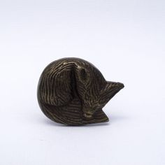 a small bronze figurine of a cat's head on a white background