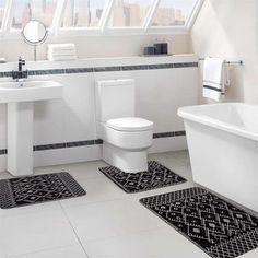 a bathroom with black and white rugs on the floor next to a bathtub