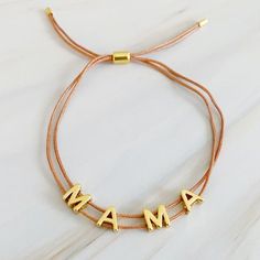 This beautiful MAMA bracelet is made of a slim satin thread with a simple golden font. Its clean, minimalist design features adjustable drawstring size for easy fitting, with each letter that moves independently around the thread. Perfect for any mom.Dimensions: approximately up to 10 inches perimeter fully adjustable with a slide18k gold plated brassLead and Nickel freeEthically sourcedMade in ChinaShips from USA Adjustable Bracelet As Gift For Mom, Adjustable Name Bracelet As Gift For Mom, Casual Gold Adjustable Friendship Bracelets, Minimalist Adjustable Custom Name Jewelry, Adjustable Gold Friendship Bracelet, Adjustable Gold Casual Friendship Bracelets, Adjustable Minimalist Name Bracelet For Everyday, Casual Gold Jewelry With Adjustable Cord, Adjustable Custom Name Friendship Bracelets For Everyday