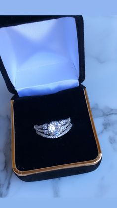 a diamond ring in a velvet box on a marble countertop with white and gold trim